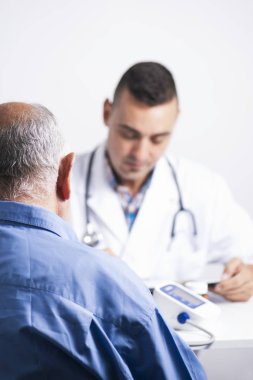 üst düzey bir beyaz hasta adam arkadan görmüş ve hem doktorlar masada oturan bir beyaz doktor adam tıbbi geçmişini veya onun tableti bir test sonuçlarını kontrol closeup
