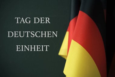 Almanya ve metin etiketi der Deutschen Einheit, gün Alman Almanca, koyu yeşil bir arka plan karşı yazılmış birlik bazı bayrakları