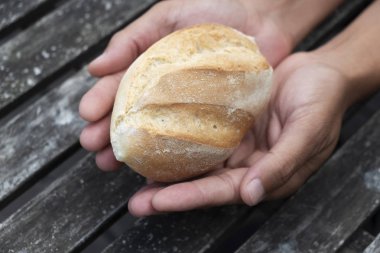 yüksek açılı görünüş bir ekmek ile beyaz bir adamın rulo rustik ahşap bir masa üzerinde onun elinde