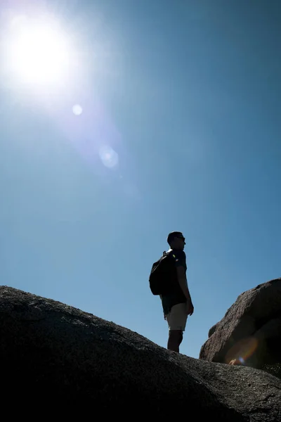 左の太陽光線とサルデーニャ イタリア バックライト付きで 岩の上部にはバックパックを持って若い白人男のクローズ アップ — ストック写真