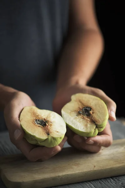 特写一个年轻的高加索男子与木瓜水果削减在他手中的一半 在一个灰色的乡间木桌 — 图库照片