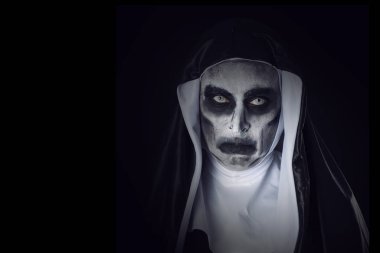 dikey soldan bazı boş alan ile siyah bir arka plan karşı tipik bir siyah ve beyaz alışkanlık giyen bir korkutucu kötü Rahibe