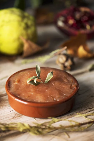 いくつかのマルメロの果実の横にある素朴な木製のテーブル上の自家製花梨チーズ陶器ボウルのクローズ アップ — ストック写真