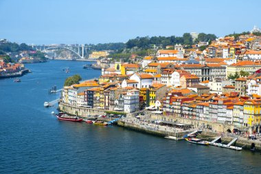 PORTO, PORTUGAL - AUGUST 29, 2018: A view of the Douro River and the old town of Porto, in Portugal, with its characteristic houses of different colors, and the Arrabida bridge in the background clipart