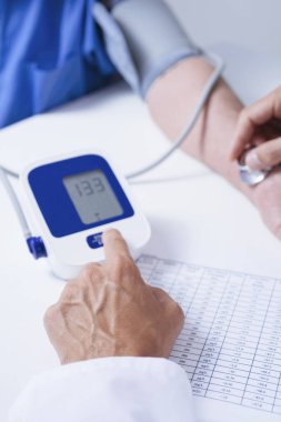 beyaz bir ceket, bir beyaz doktor adam closeup üst düzey bir beyaz hasta adamın kan basıncı tansiyon aleti ile ölçme.