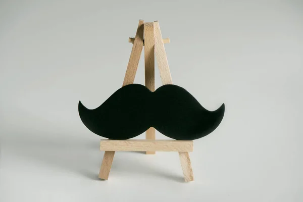 Une Moustache Noire Sur Chevalet Bois Sur Fond Blanc Cassé — Photo