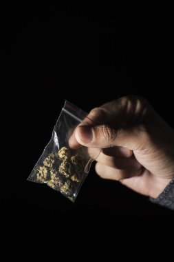 Biraz esrar tomurcukları elinde siyah bir arka plan biraz boş alan ile bir plastik torba ile genç bir beyaz adam closeup