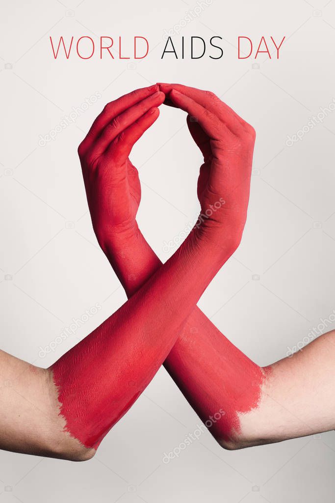 closeup of the arms of two men painted red forming a red awareness ribbon and the text world aids day against an off-white background