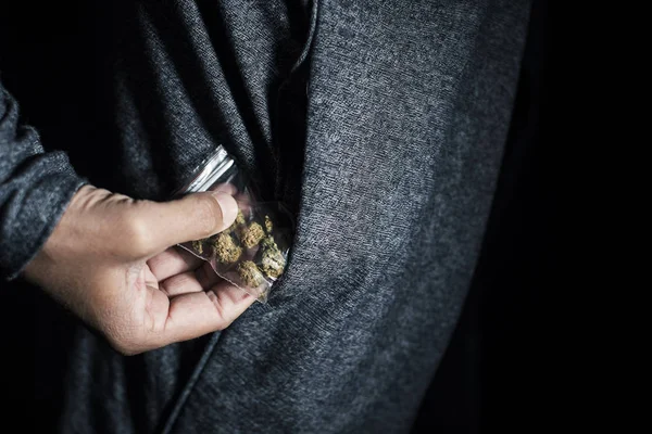 特写镜头的一个年轻的高加索男子采取或脱下一个塑料袋与一些大麻芽从他的夹克口袋里 — 图库照片