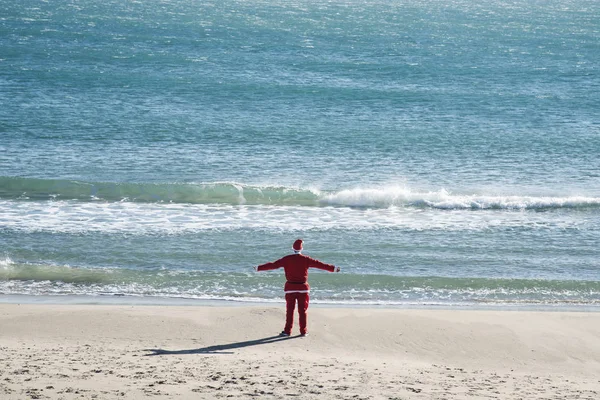 Ung Man Som Bär Santa Kostym Sedd Bakifrån Stående Stranden — Stockfoto