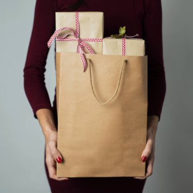 Kağıt alışveriş çantası hediye tam bir off-beyaz arka plan üzerinde tutan genç bir beyaz kadın closeup