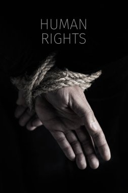 closeup of a man with his hands tied behind his back with rope, and the text human rights against a black background clipart