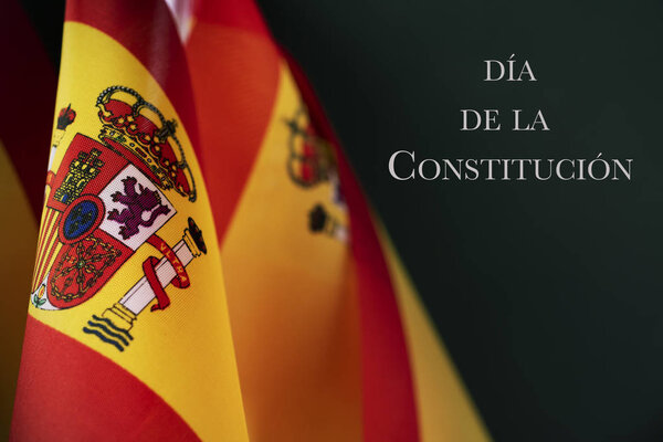 некоторые испанские флаги и текст dia de la constitucion, день конституции написан на испанском языке, на темно-зеленом фоне
