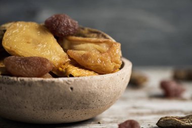 closeup dolu bir rustik toprak kase kuru meyve, armut, şeftali, muz, çilek, elma veya kayısı, ahşap bir masa üzerinde gibi çeşitli