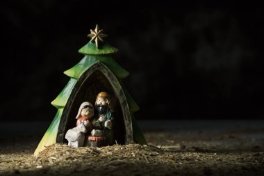 Kutsal Aile, Çocuk İsa, Meryem ve Aziz joseph, sağda bir boşluk ile karanlık bir arka plan karşı bir rustik Doğum sahnesi