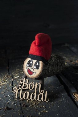 El yapımı tio de nadal, catalonia, İspanya ve metin bon nadal, Katalanca, gri bir rustik ahşap yüzey üzerinde yazılı mutlu Noeller tipik bir Noel karakter biraz ışıklı