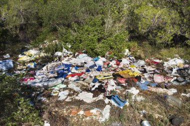 view of a pile of garbage illegally dumped in an open dump by a rural lane clipart