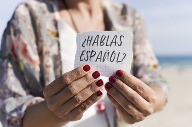 Açık havada bir parça kağıda soru hablas espanol ile gösterilen Kafkas bir kadın closeup, İspanyolca olarak yazılı İspanyolca biliyor musunuz