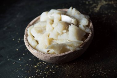 masada bir koyu yeşil, Katalan xato, bir salata ile ham cod hazırlamak için ana madde bir rustik toprak kapta tuz COD tuzlama bazı closeup şeritler