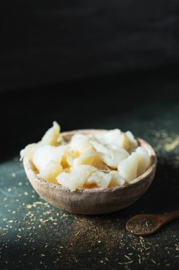 masada bir koyu yeşil, Katalan xato, bir salata ile ham cod hazırlamak için ana madde bir rustik toprak kapta tuz COD tuzlama bazı closeup şeritler