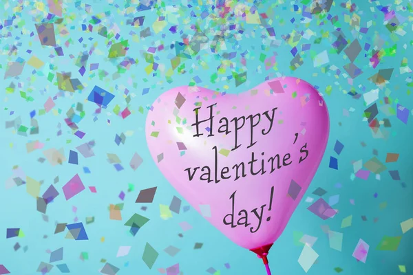 一个粉红色的心形气球与文本快乐情人节和一些五彩纸屑在蓝色背景 — 图库照片