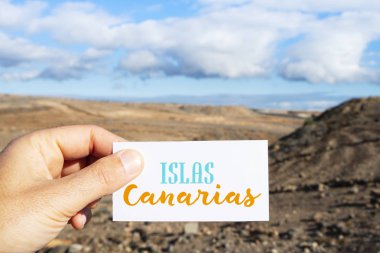metinle Islas Canarias, Kanarya Adaları, Kanarya Adaları, İspanya kuru bir manzara önünde İspanyolca olarak yazılı bir tabela holding beyaz bir adamın elini closeup