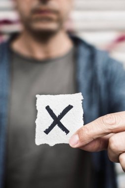 closeup of a young caucasian person holding a piece of paper with a X written in it, for the third gender category clipart