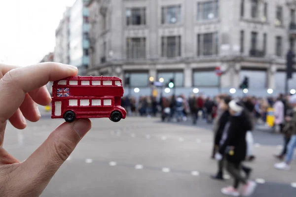 一个白种人手拿着一辆红色双层巴士的缩影的特写镜头 典型的伦敦 在街上 — 图库照片