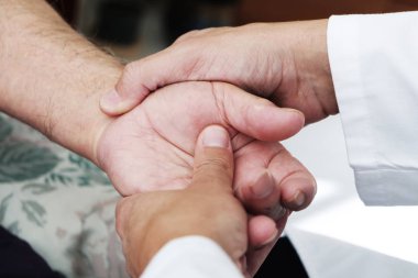 evinde ya da bir hemşirelik evde bir üst düzey beyaz hasta adamın elini hareket bir beyaz adam, beyaz bir ceket, closeup