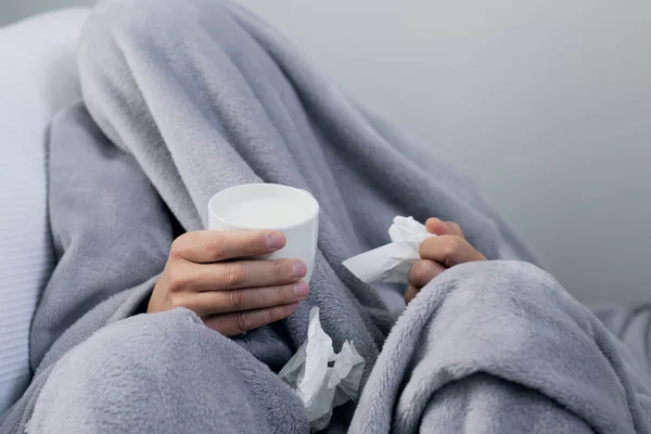 一个生病的年轻白种人在家里的特写镜头 覆盖着浅灰色柔软的毯子 热身与一杯热 Mil — 图库照片