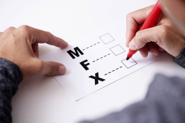 yaklaşık üçüncü cinsiyet Kategori için kadın erkek, F için M harfleri ile bir form içinde X ve X üzerinde işaretlemek için genç bir beyaz kişi closeup