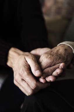 closeup of a young caucasian man holding the hand of an old caucasian woman with affection clipart