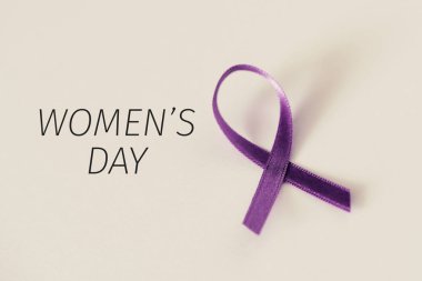 a purple awareness ribbon and the text womens day, on an off-white background clipart