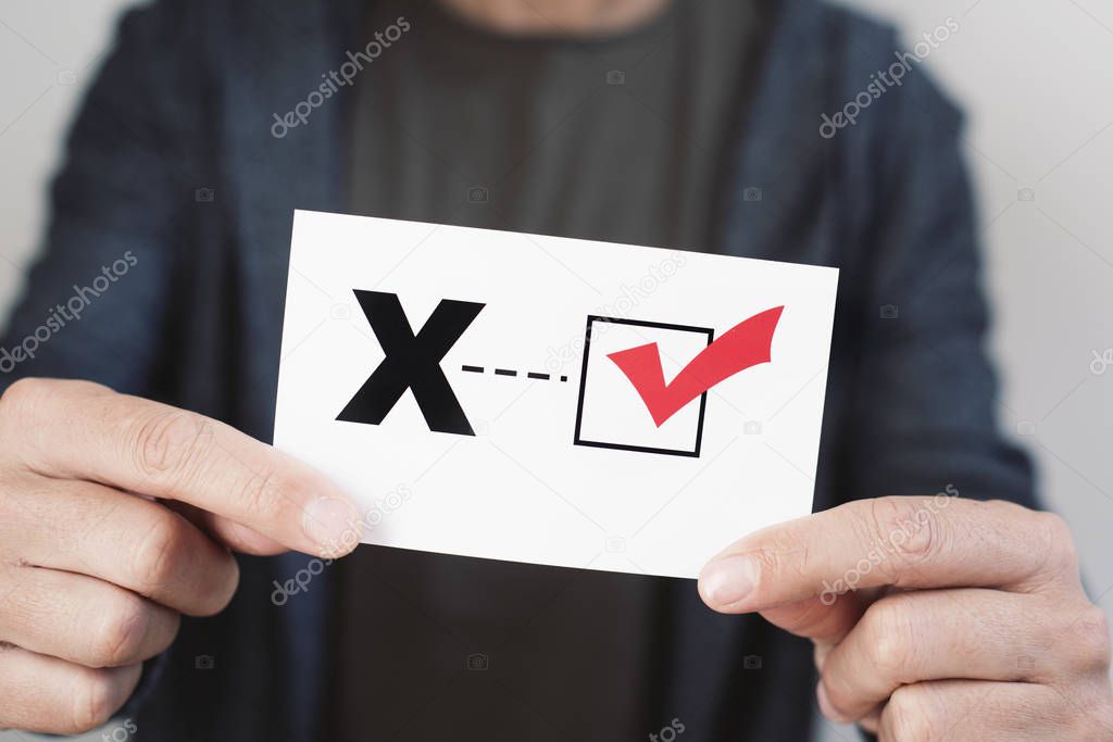 closeup of a young caucasian person holding a piece of paper with a X written in it, for the third gender category