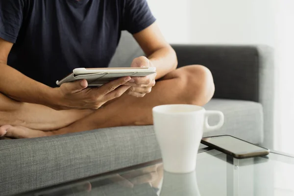 Muž sedět se zkříženýma nohama v pohovce v tabletu — Stock fotografie