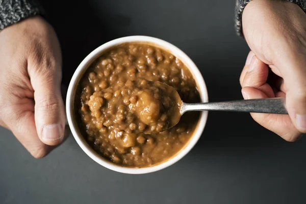 Homme mangeant une soupe de lentilles — Photo