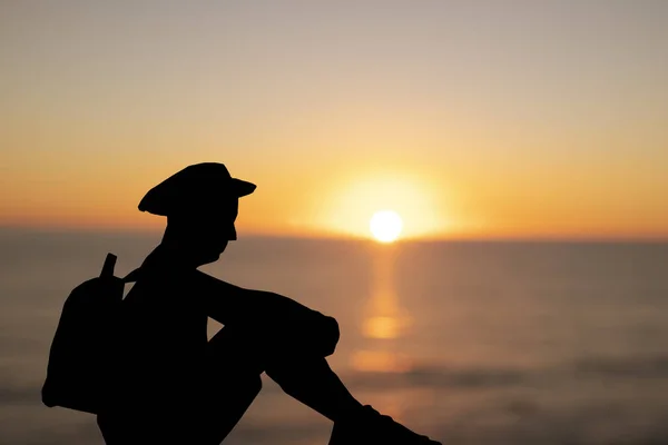 Silhouet van een backpacker man zit bij zonsondergang — Stockfoto