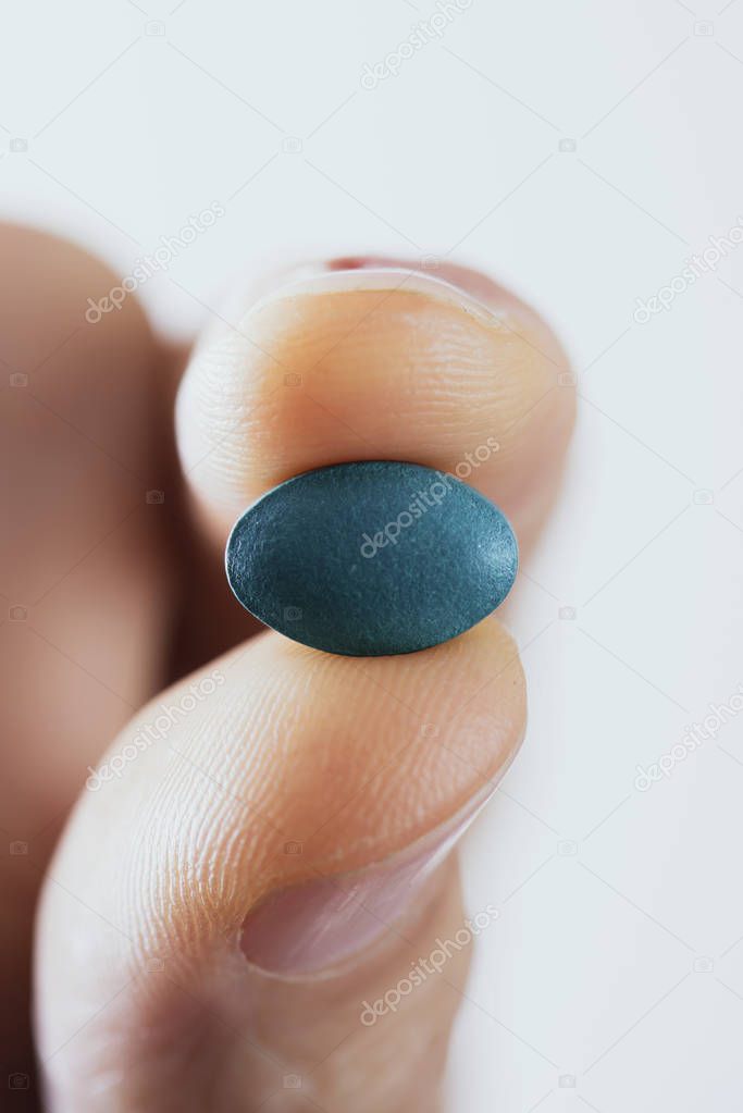 young man with a blue pill in his hand