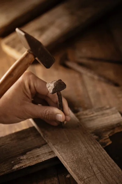 Hombre clavando un clavo en un cros de madera — Foto de Stock