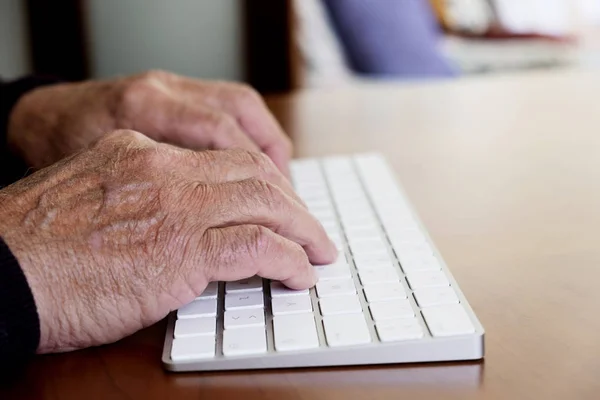 Alter kaukasischer Mann tippt in eine Tastatur — Stockfoto