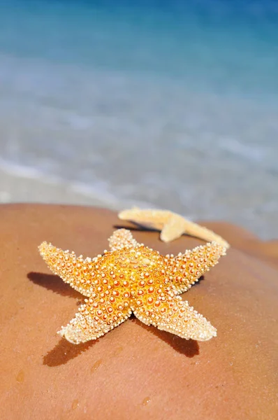 Estrelas-do-mar nas costas de um jovem na praia — Fotografia de Stock