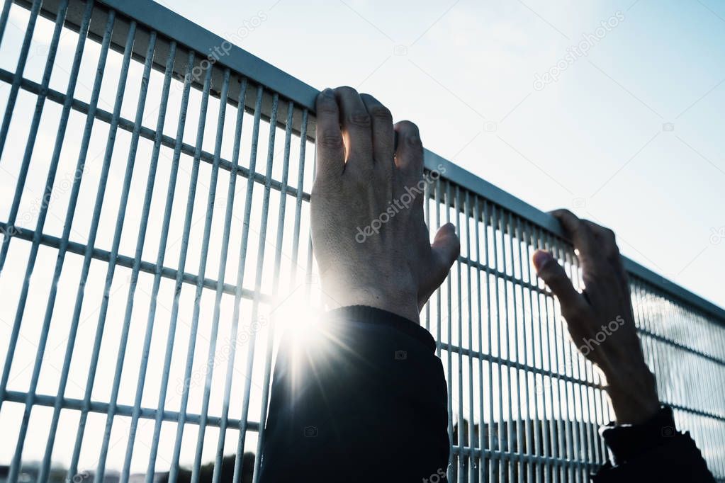 man climbing up a metal fence