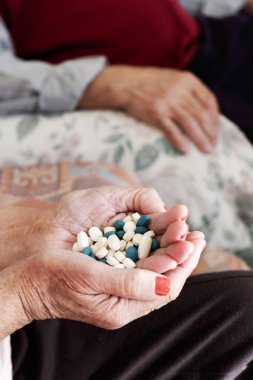 senior woman with a pile of pills in his hand clipart