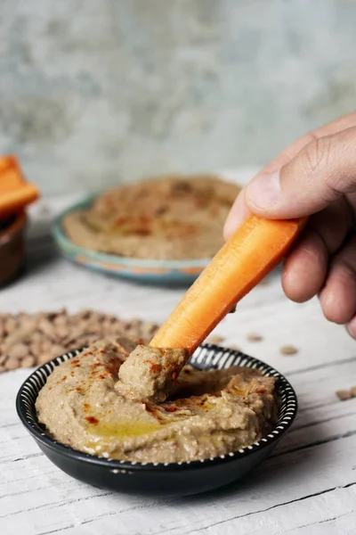 Mojar la zanahoria en un hummus casero de lentejas — Foto de Stock