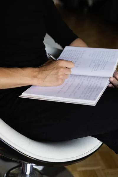 Hombre escribiendo en un cuaderno sentado en un chai —  Fotos de Stock