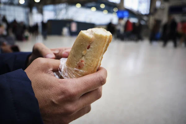 Man eating a sandwich in a train or tram statio — Stock Photo, Image