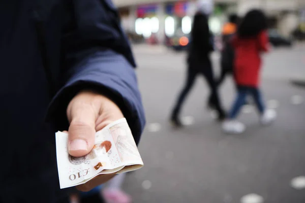 Чоловік пропонує кілька фунтів стерлінгів банкноти — стокове фото