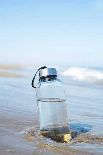 Garrafa de água reutilizável na praia — Fotografia de Stock