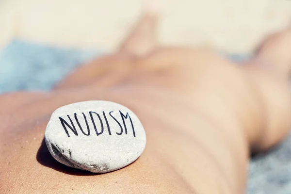 男人躺在沙滩上和文本裸体主义 — 图库照片