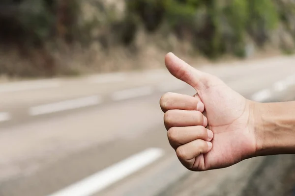 Joven haciendo autostop en una carretera secundaria —  Fotos de Stock